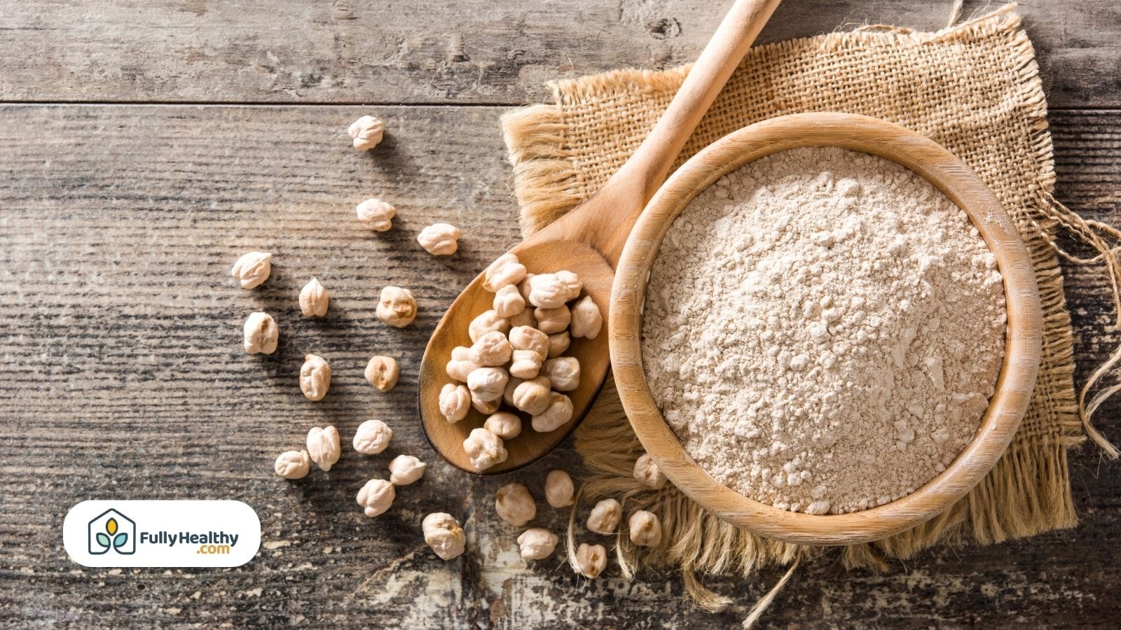 Chickpea flour in wooden bowl with dried chickpeas on wooden surface