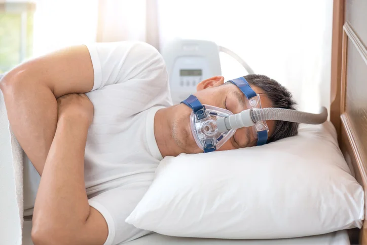 A person lying on bed using a ventilator