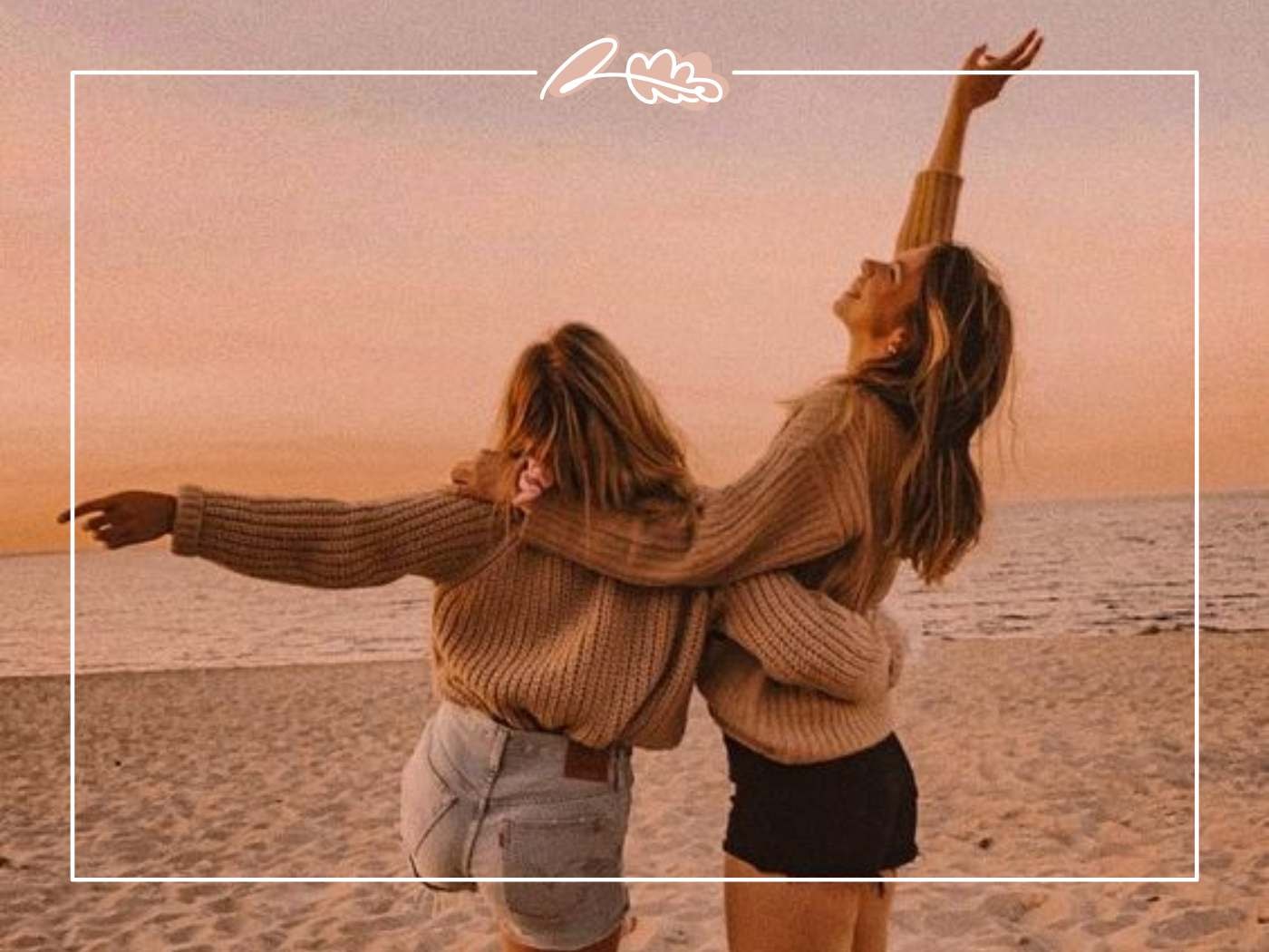 Two women at the beach, embracing and smiling at sunset, enjoying a carefree moment by the sea.