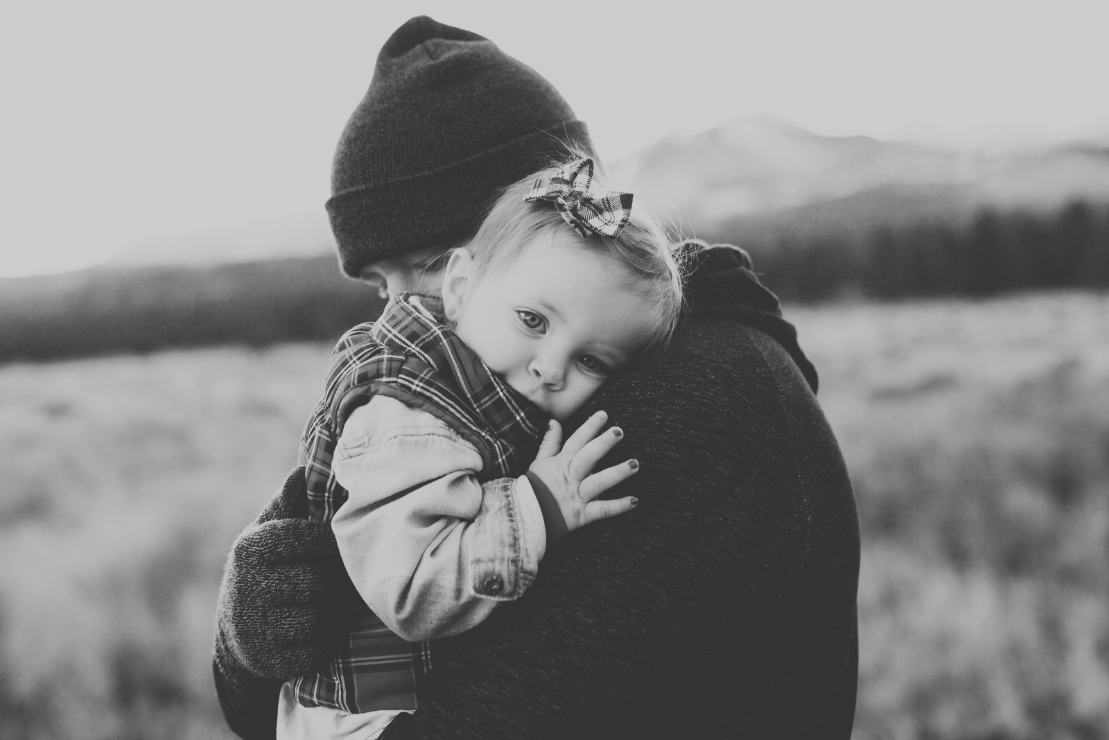 black and white photo of a dad hugging his little girl while she is looking into the camera