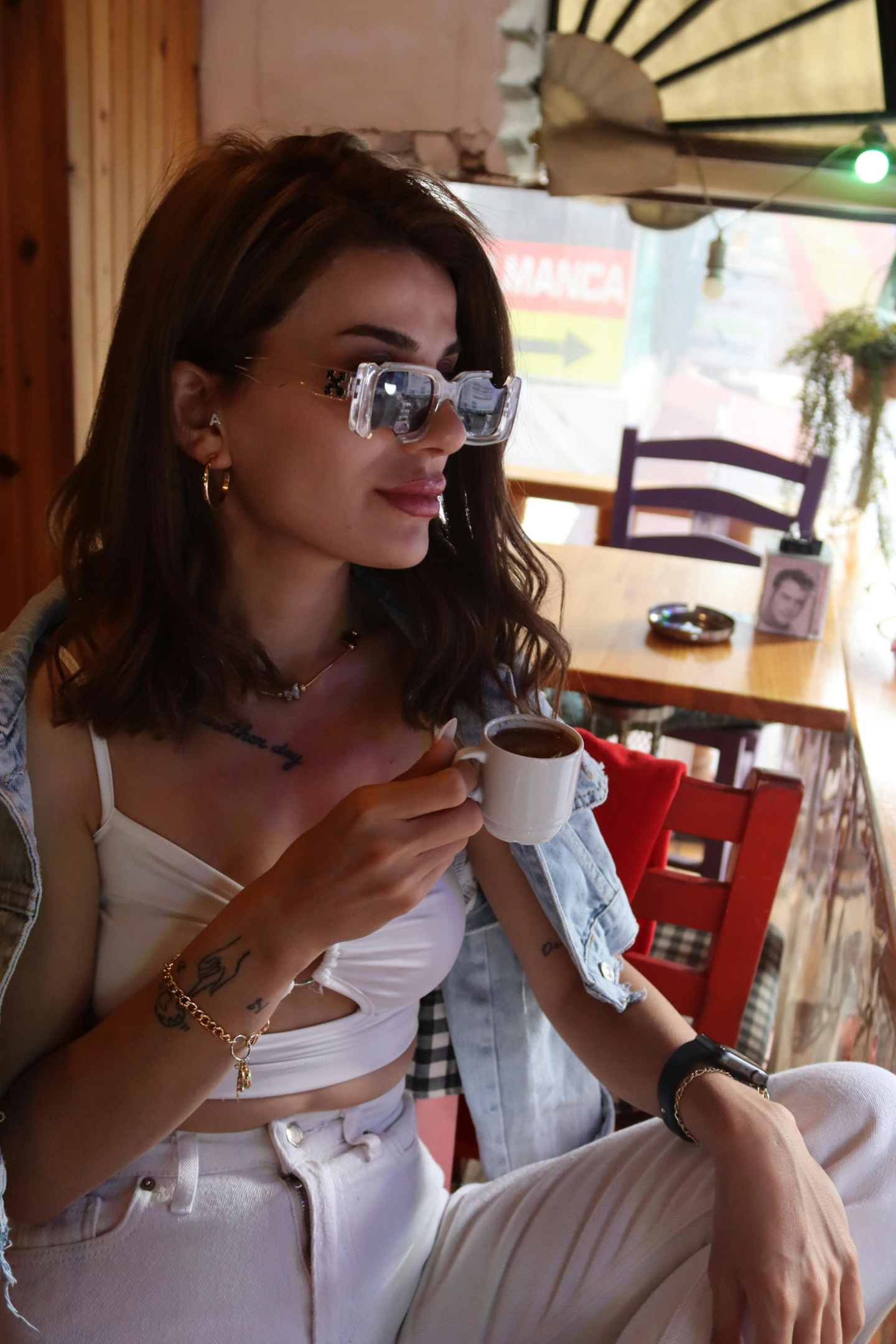 Woman in summer clothes/sunglasses holding an espresso in cafe