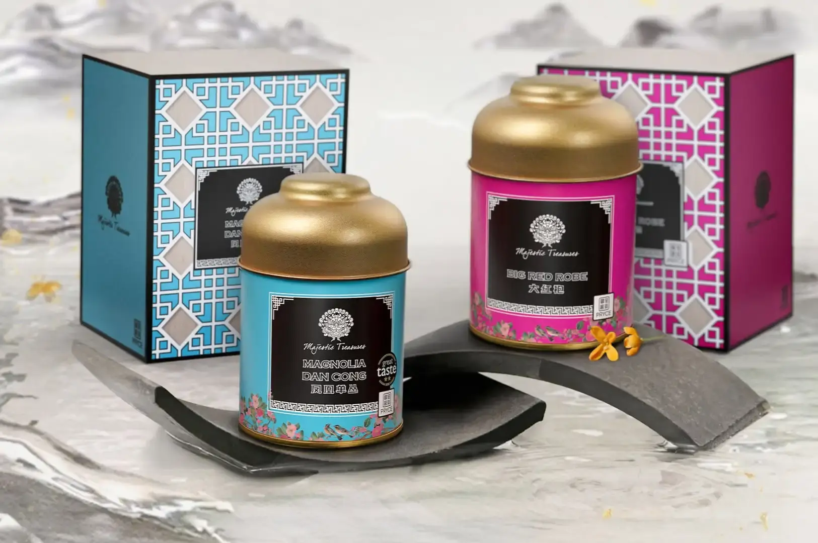 Two vibrant tea tins—one bright blue labeled "MAGNOLIA DAN CONG" and one magenta labeled "BIG RED ROBE"—rest on dark, curved tile display stands over a light grey marble surface. Behind each canister sits its corresponding gift box featuring intricate geometric lattice patterns in matching blue and pink hues.