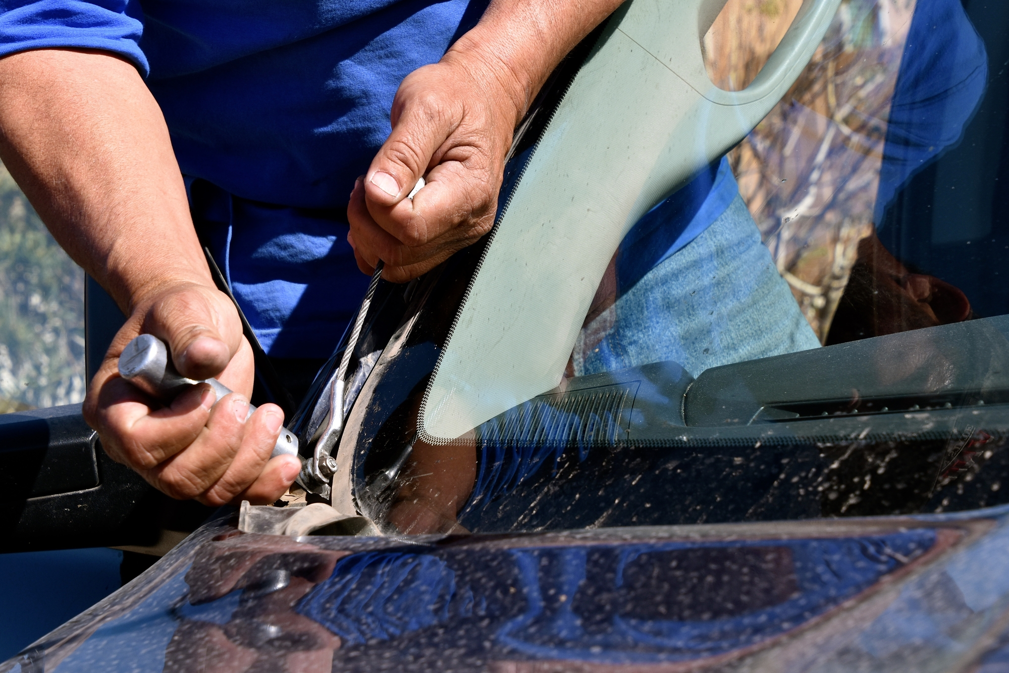 Auto glazier cutting old glue between windshield and frame