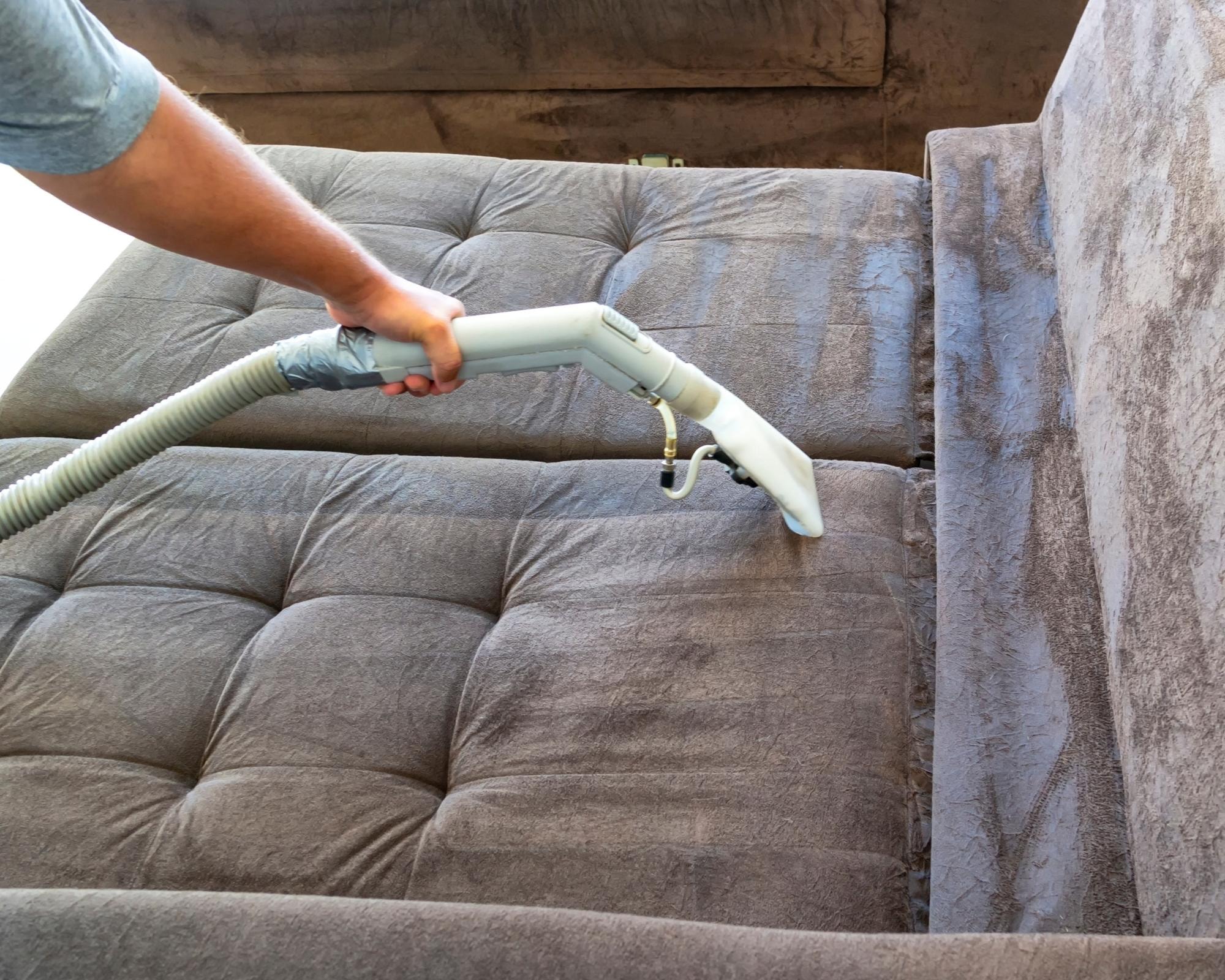 Professional deep cleaning a brown tufted sofa with an upholstery cleaner by Cleanology SG, showcasing expert sofa cleaning services to remove dirt and stains for a pristine finish in Singapore.