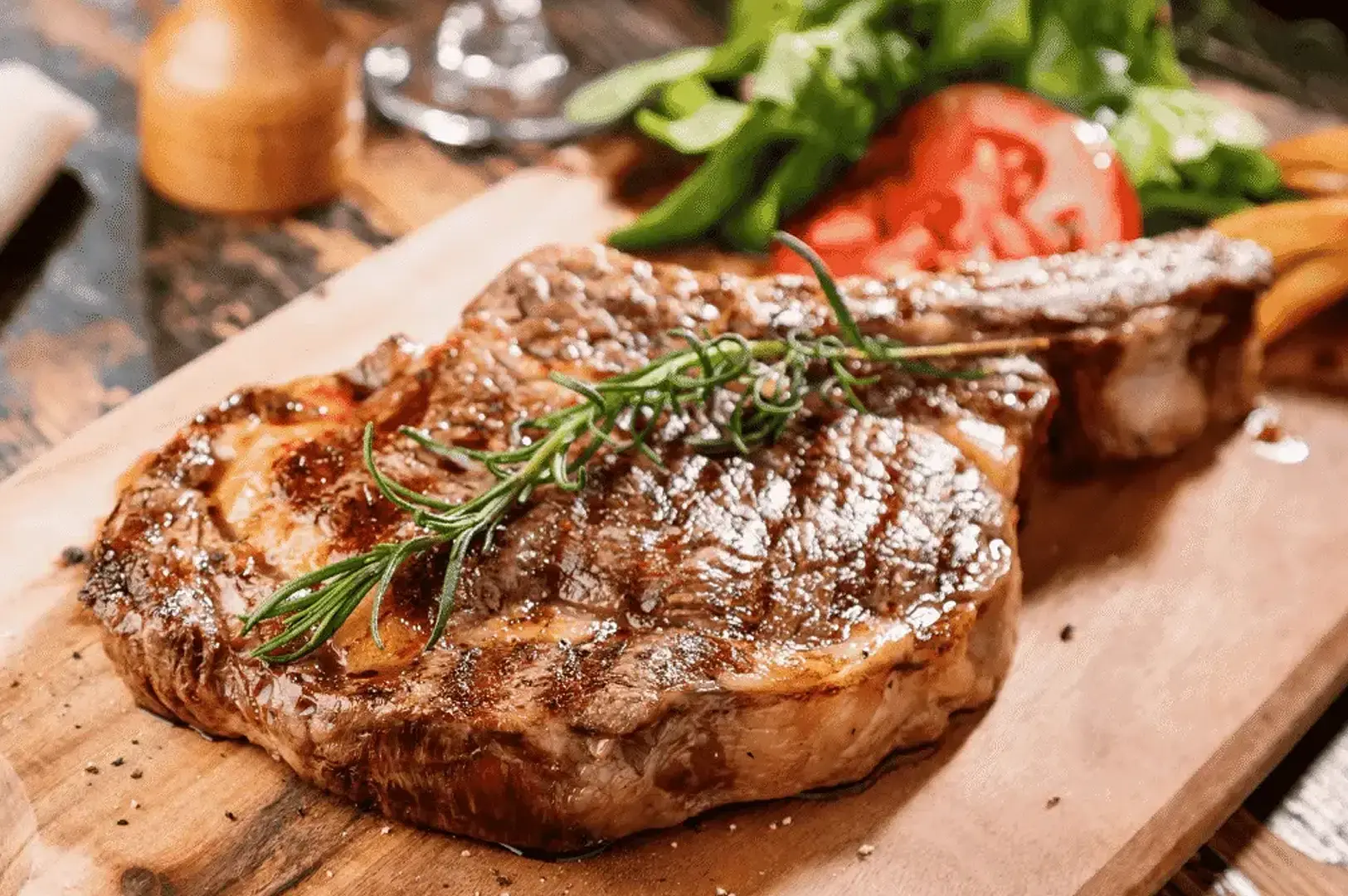 Singapore steakhouse ribeye steak served on a wooden board with rosemary, vegetables and roasted sides