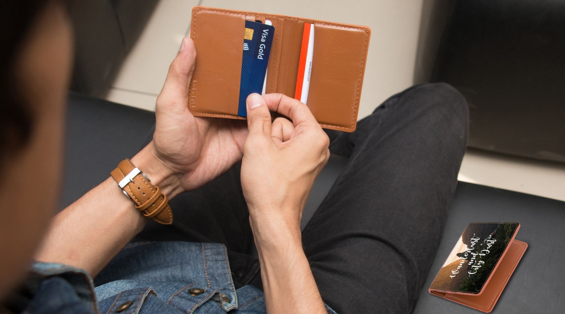 Young man examining multiple credit cards in a brown leather wallet.