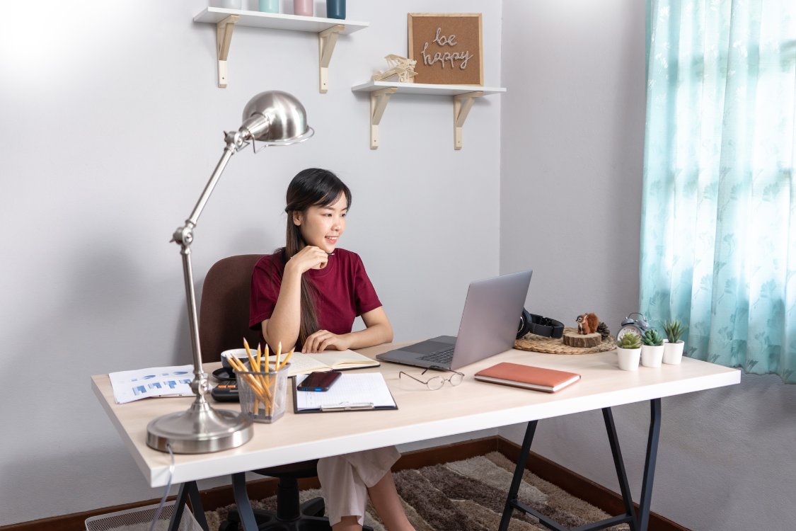 Filipino professional working remotely in a home office with laptop and planner.