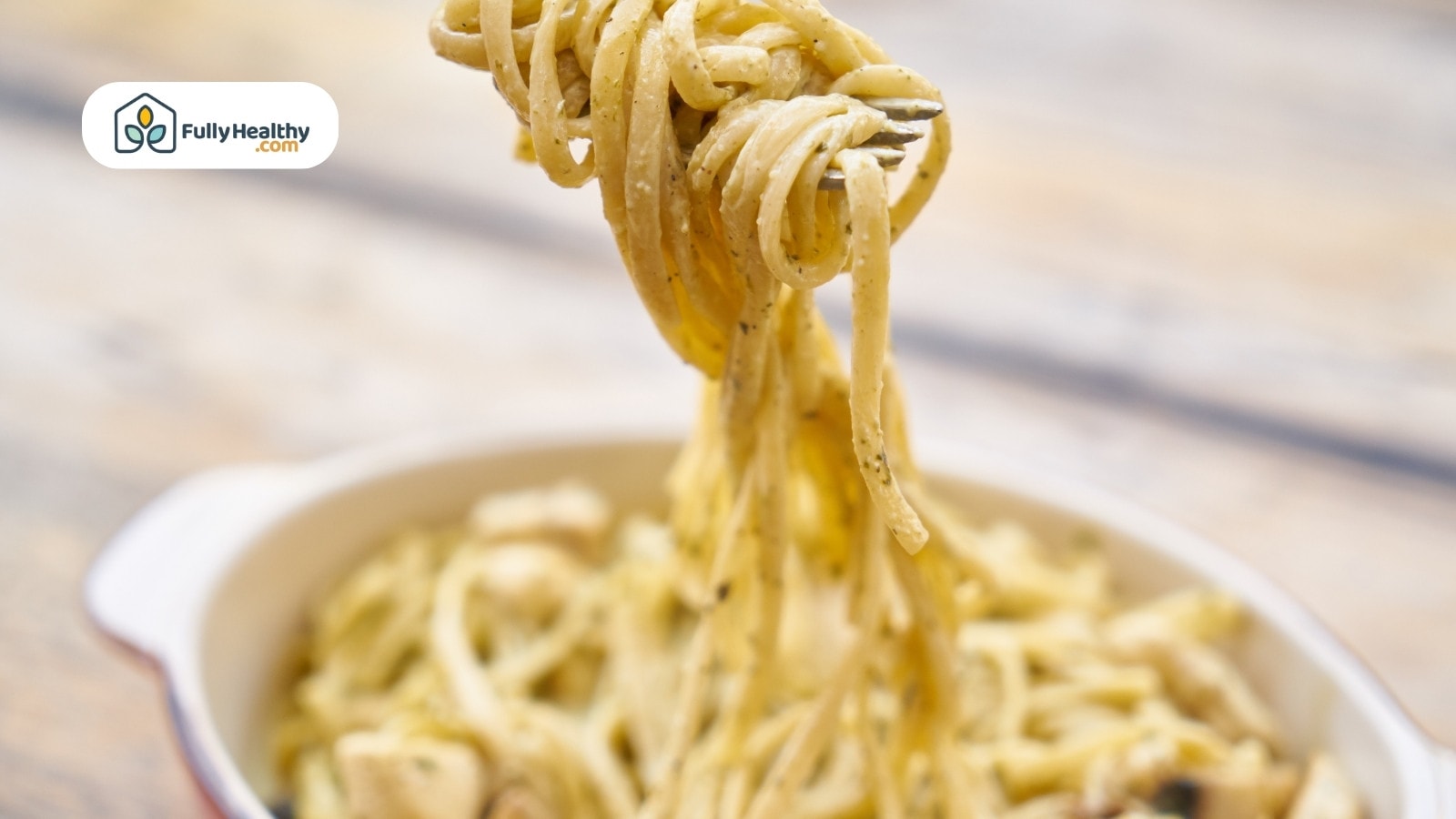 Fork lifting creamy spaghetti from a bowl of pasta with sauce