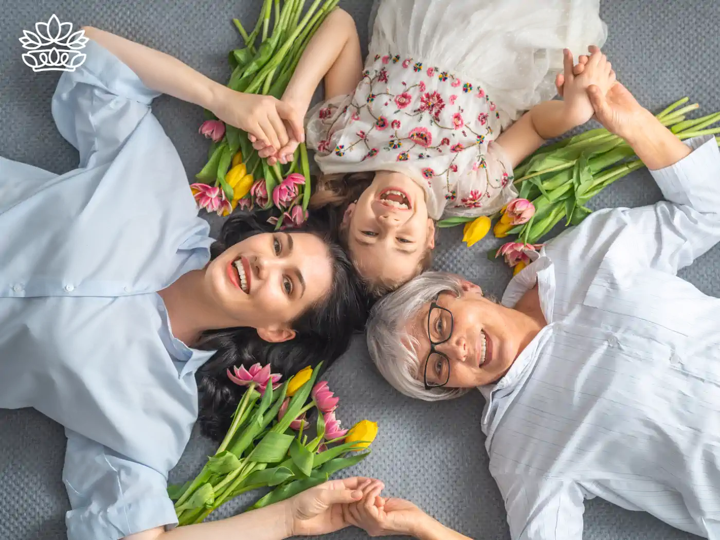 Three generations of women lying on the floor with flowers, smiling at the camera. Fabulous Flowers and Gifts. Collection: Women's Day.