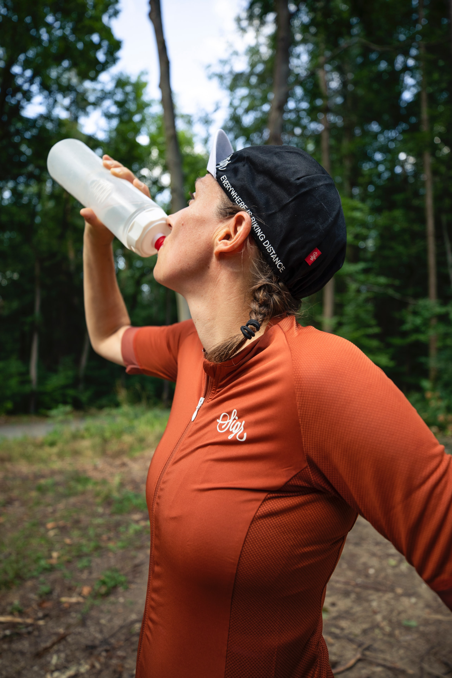 Mulher ciclista se hidratando. Crédito: Unsplash