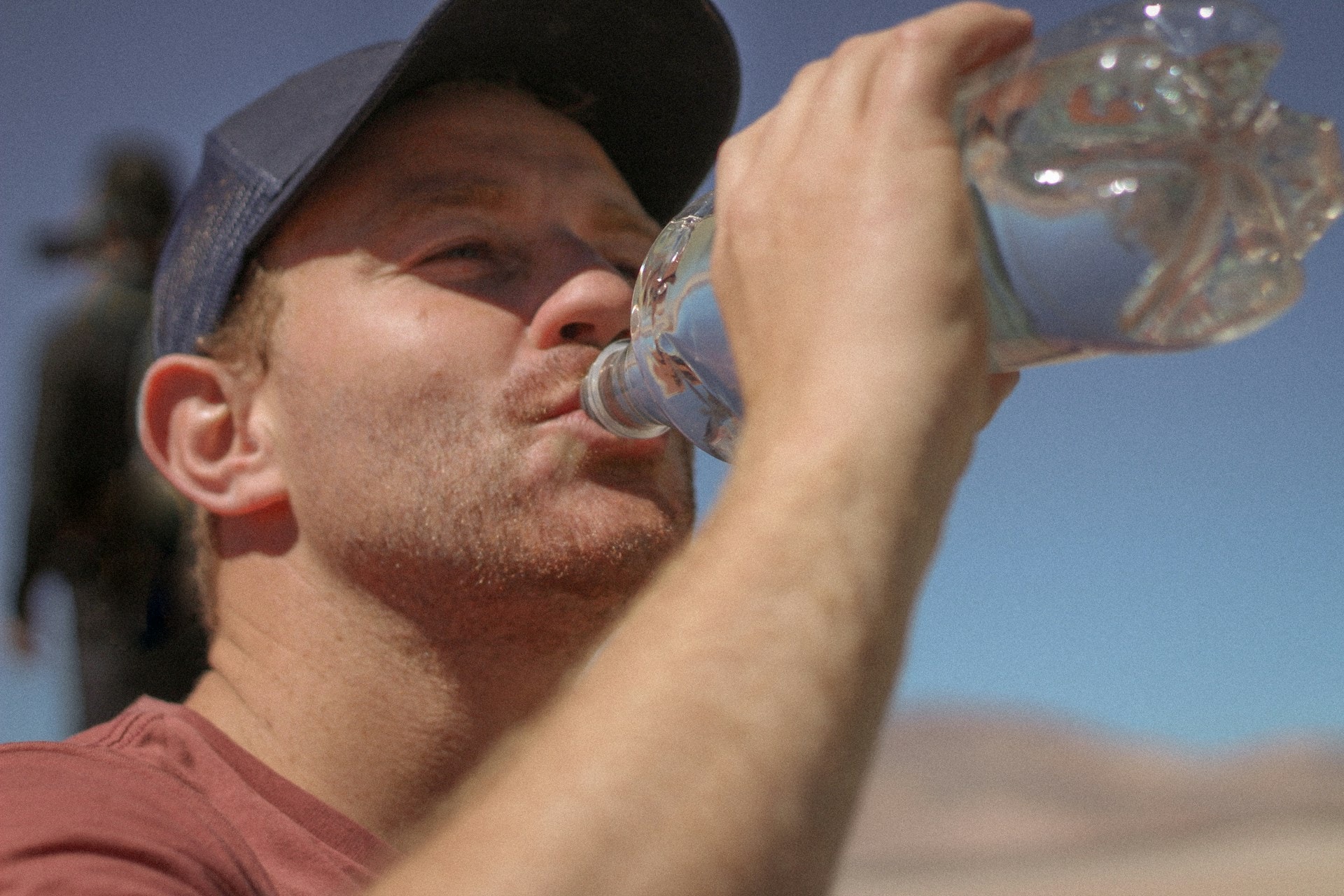 Man drinking water from a bottle outdoors to stay hydrated, a simple self-care step that may help with colon pain lower back linked to constipation.