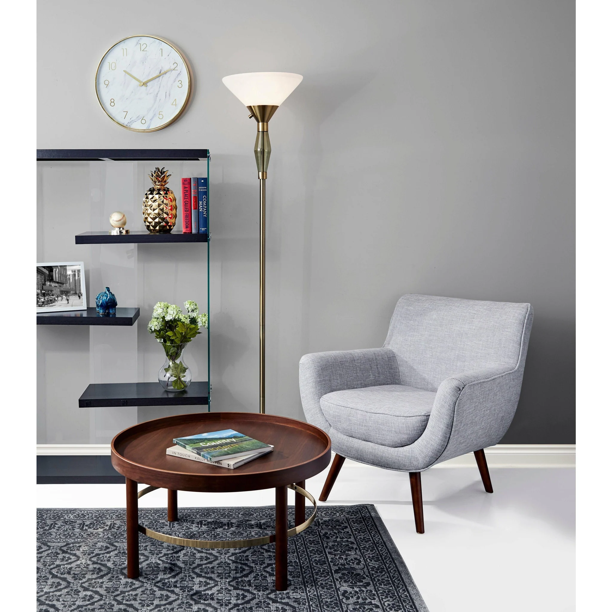 Modern living room corner featuring a brass torchiere floor lamp, grey armchair, and minimalist decor.