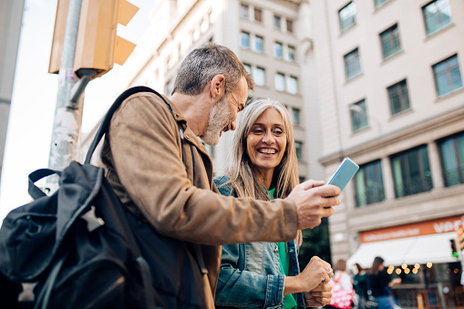 Man and woman in the city looking at a blue cell phone while laughing