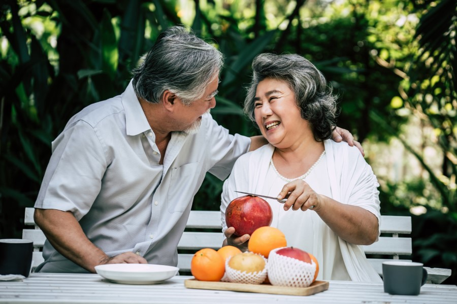 older couple sitting on a park bench 