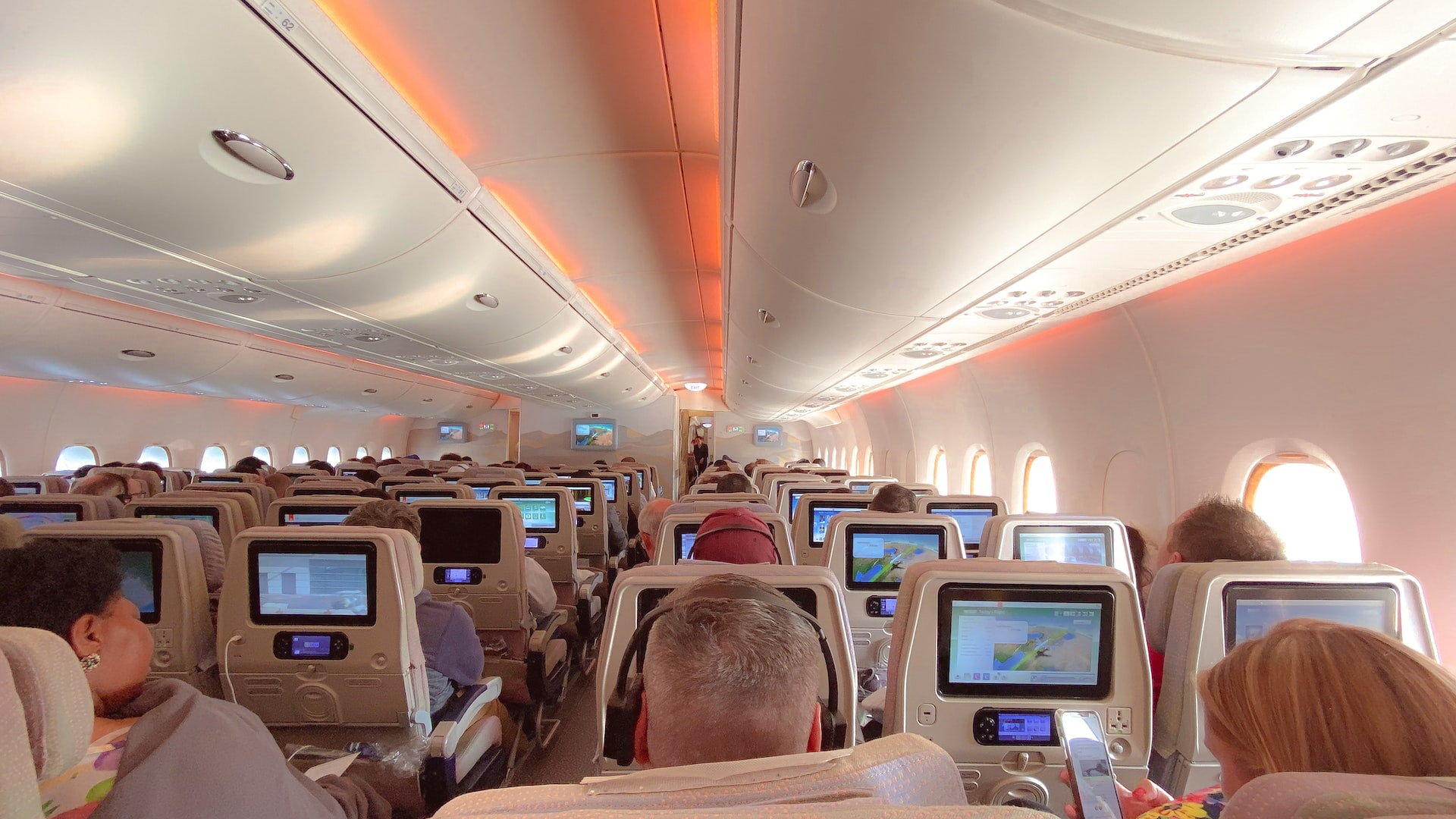 A spacious aircraft cabin with people sitting on their seats.