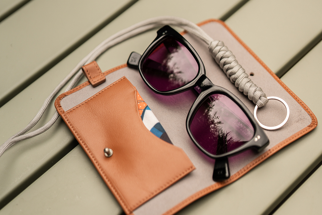 Aerial view of square black sunglasses frame beside tan leather case