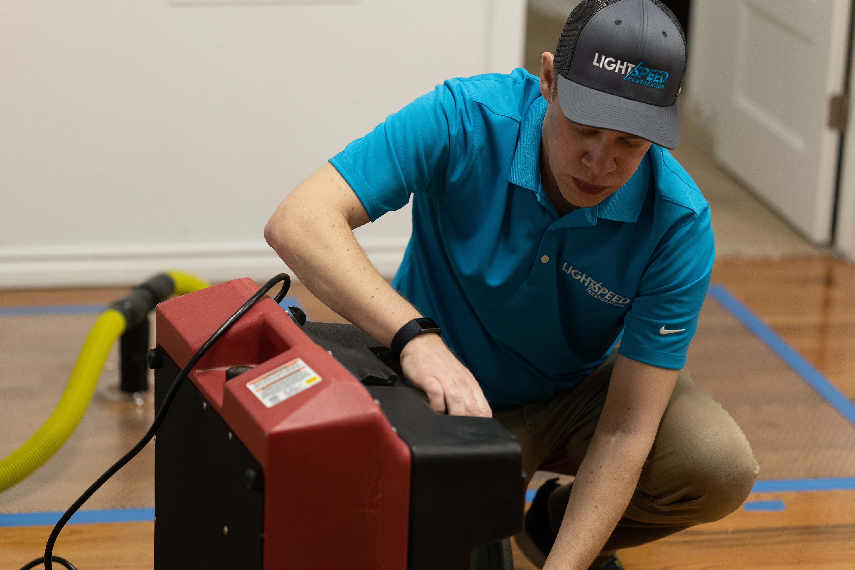 A professional restoration team is seen working in a residential setting, utilizing industrial drying equipment to address water damage caused by potential slab leaks. The scene highlights their efforts to mitigate mold and mildew growth and ensure the structural integrity of the home's foundation.