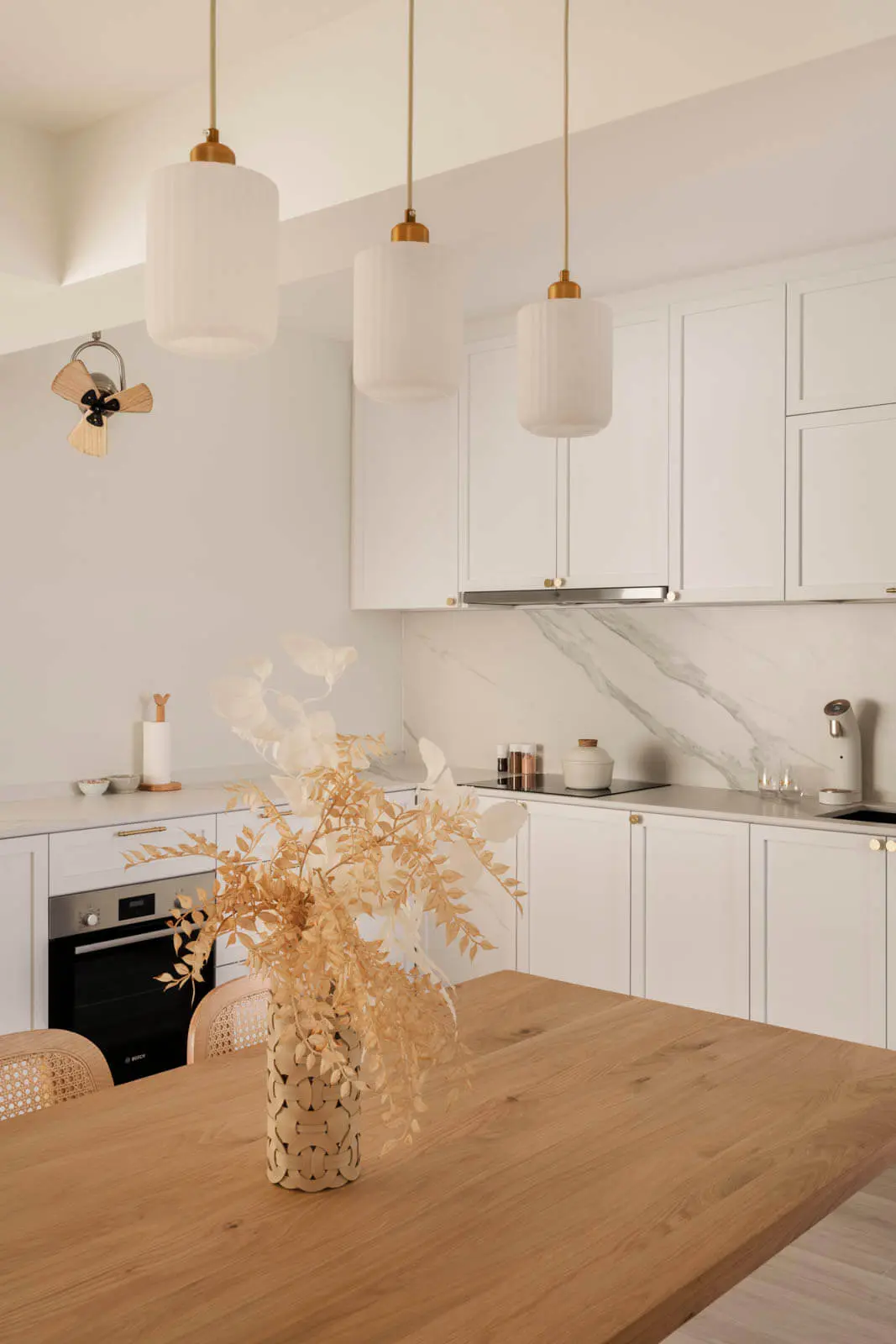 Bright Scandinavian kitchen featuring white smart pendant lights above a solid-oak island and marble-vein backsplash.