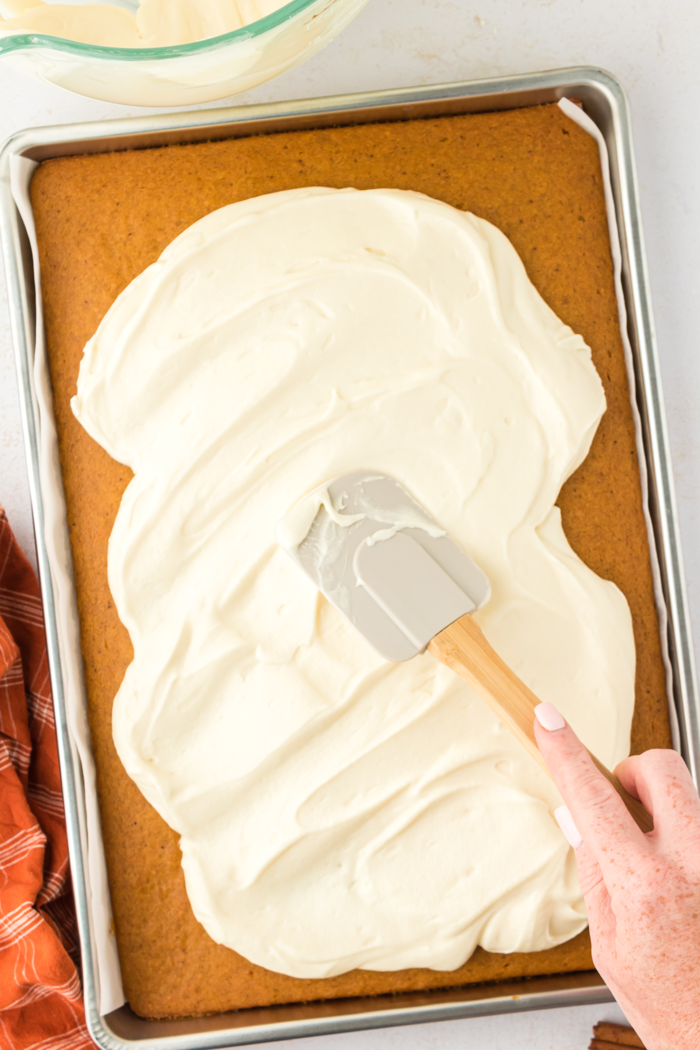 cream cheese frosting spread on top of a pan of pumpkin bars