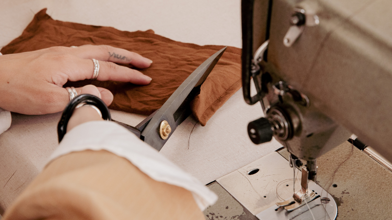 A person using scissors to cut rayon fabric on a sewing machine