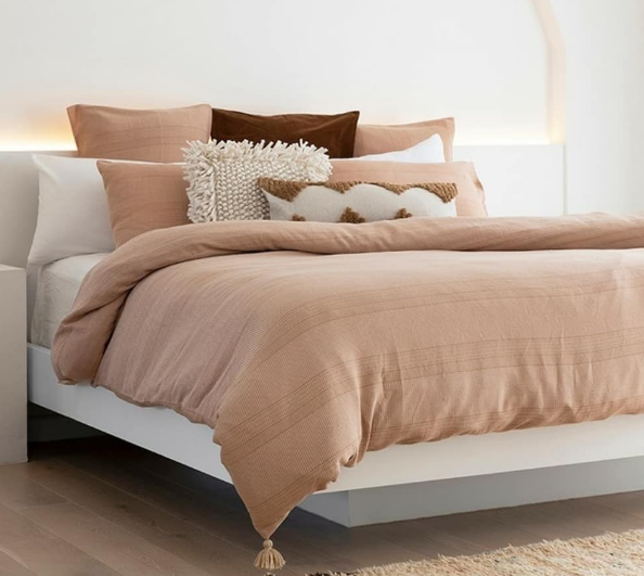tan bedding with tassels and textured throw pillows