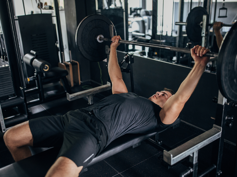 An image showing a person performing a bench press with a barbell.