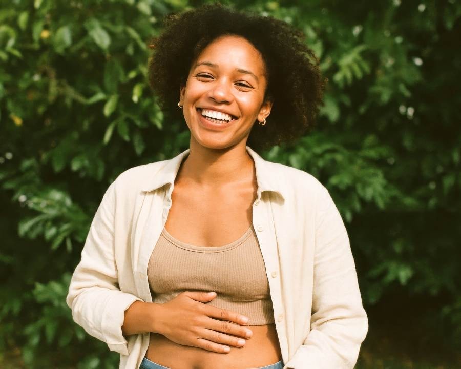 Woman smiling holding her gut with an improve digestion because of The Good Stuff