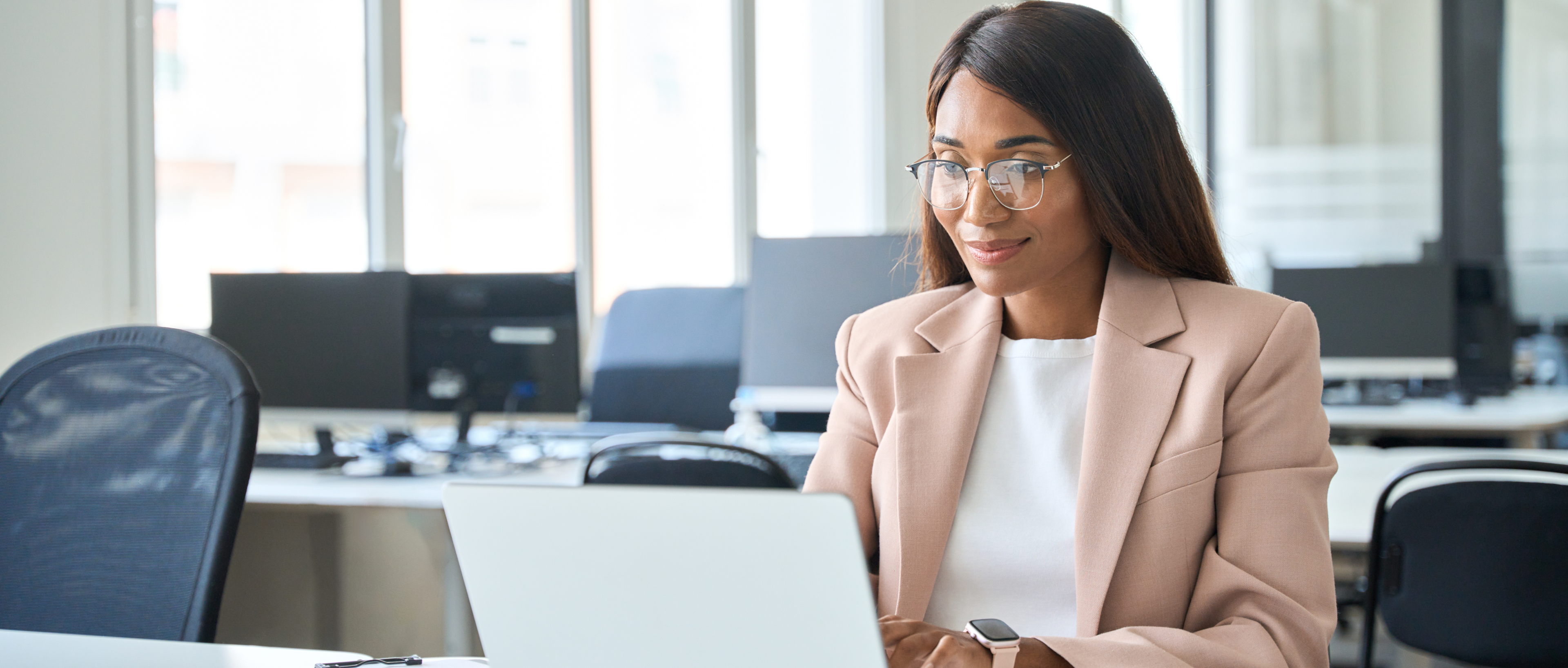 An HR consultant sitting in an office, creating a satisfaction survey on her laptop.