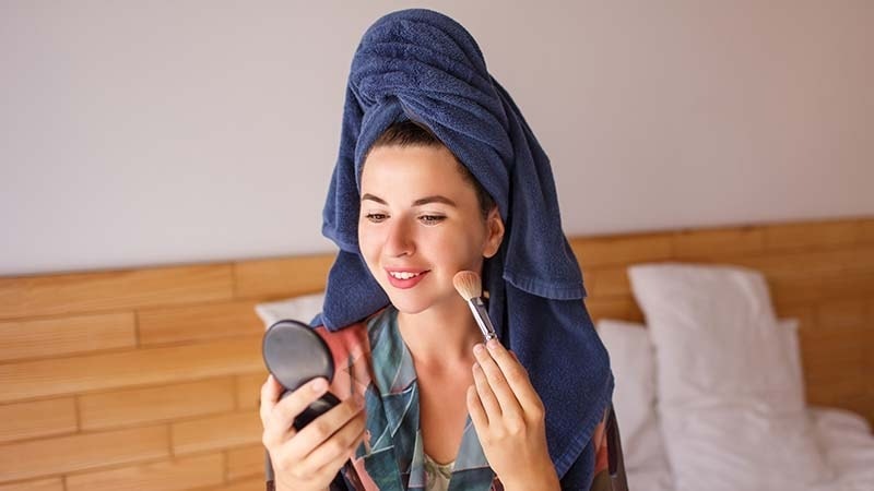 A woman in a towel doing her makeup