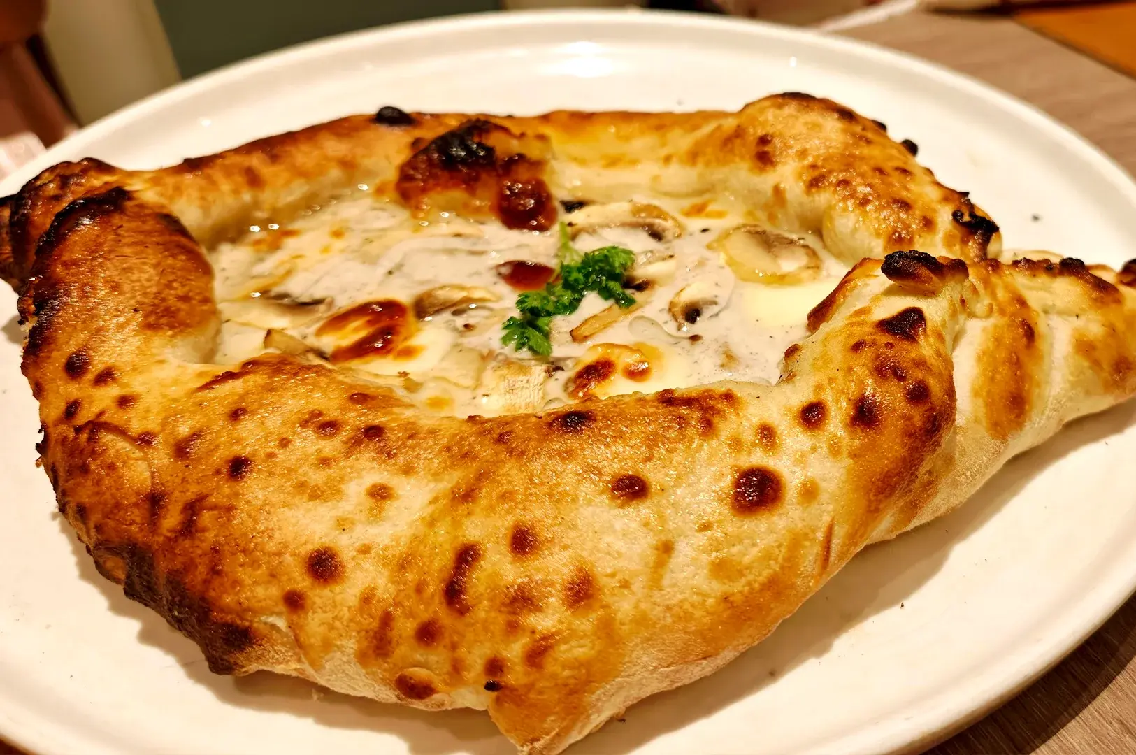 Funghi e tartufo boat pizza with a creamy mushroom and truffle base, showcasing authentic halal-Italian dining at Kucina Italian Restaurant.