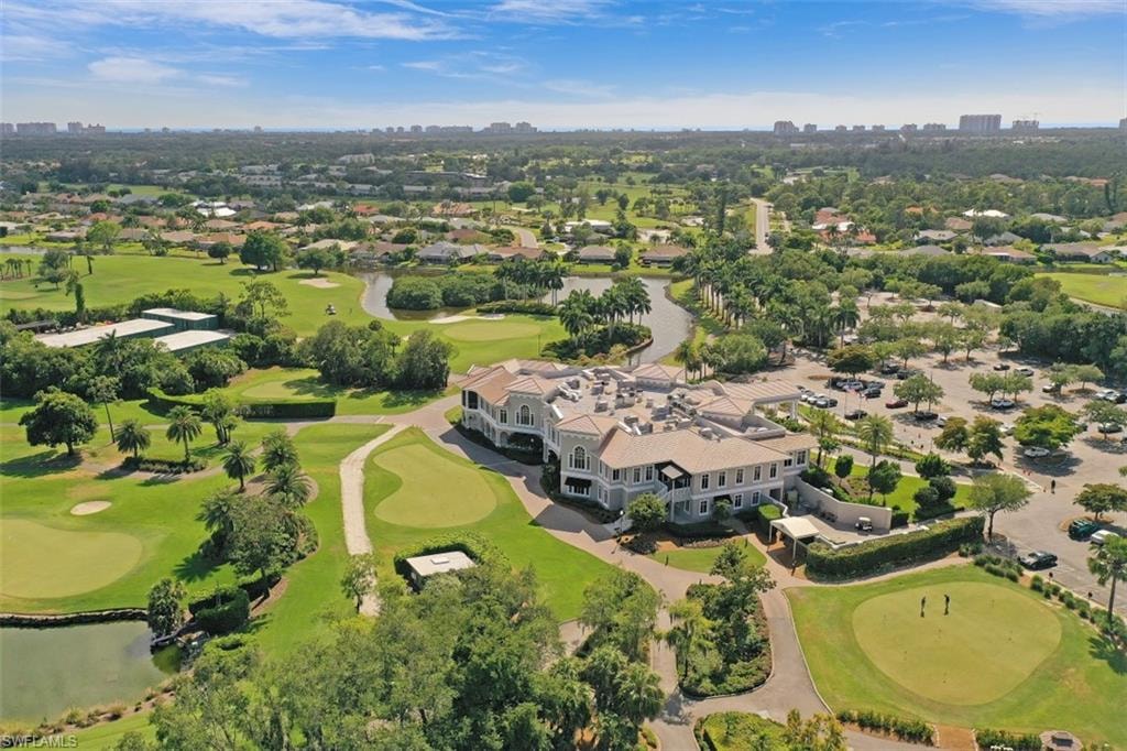 The image depicts a championship golf course in Imperial Golf Estates, Naples, FL, featuring rolling hills and serene, spring-fed lakes. Golfers can be seen enjoying a sunny day as they walk along the scenic fairways, surrounded by breathtaking views of the lush landscape.