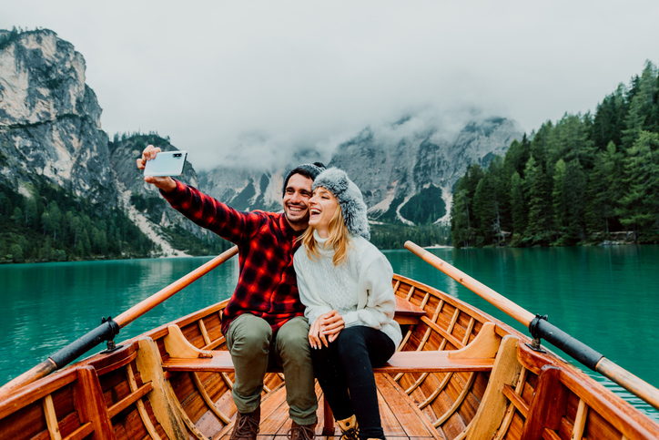 Happy young couple on a canoe surrounded by snow covered mountains. 