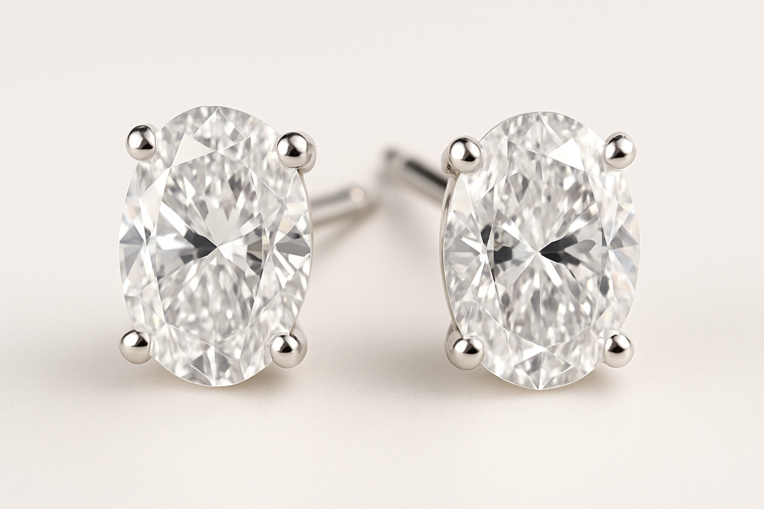 Auskarai su ovalo formos deimantais, įstatytais į elegantišką keturių kojelių tvirtinimą, neutraliai šviesiame fone