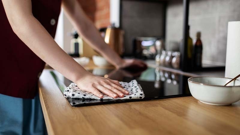 A woman wiping clean a glass stove top