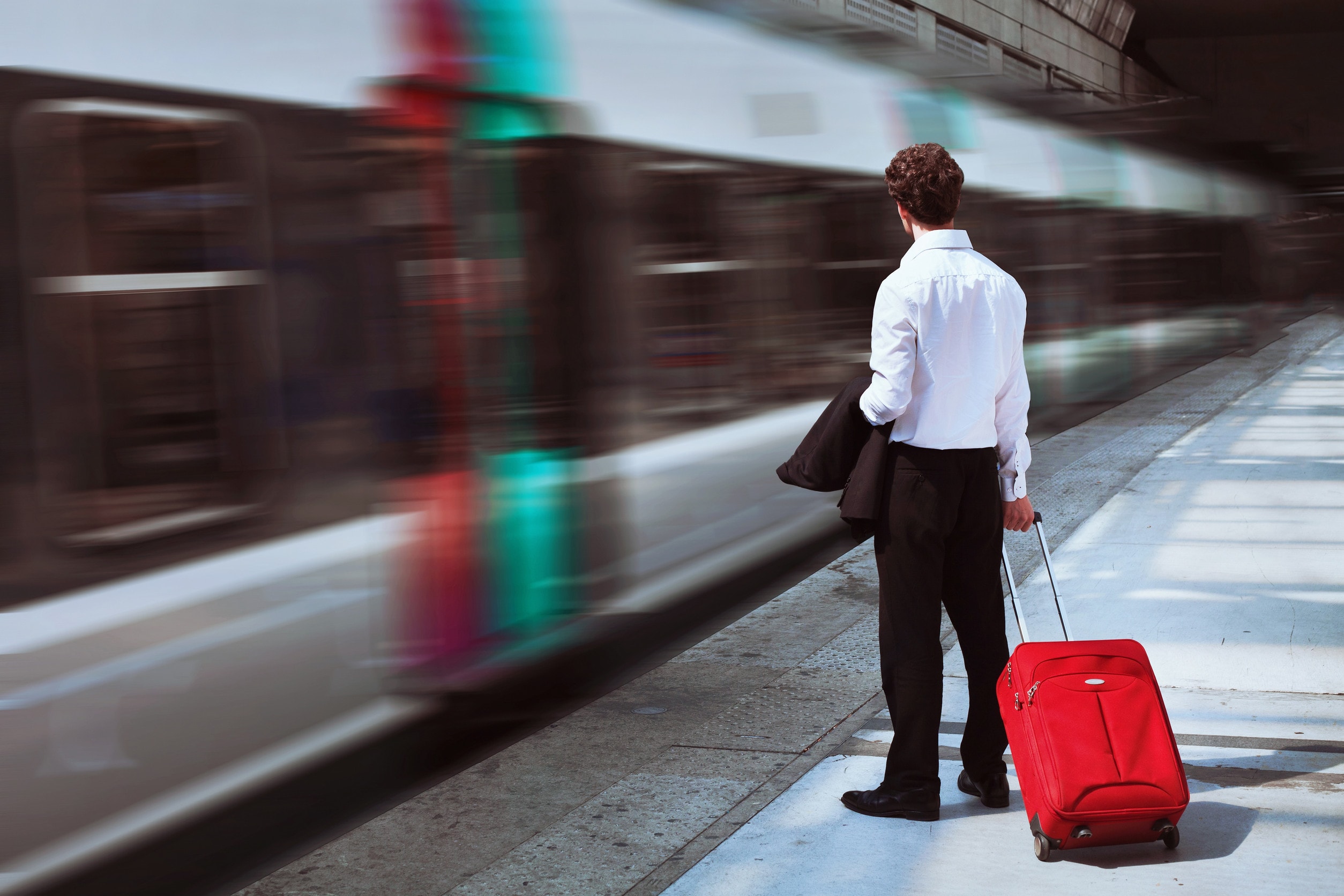 A man stands on a platform as a train speeds past