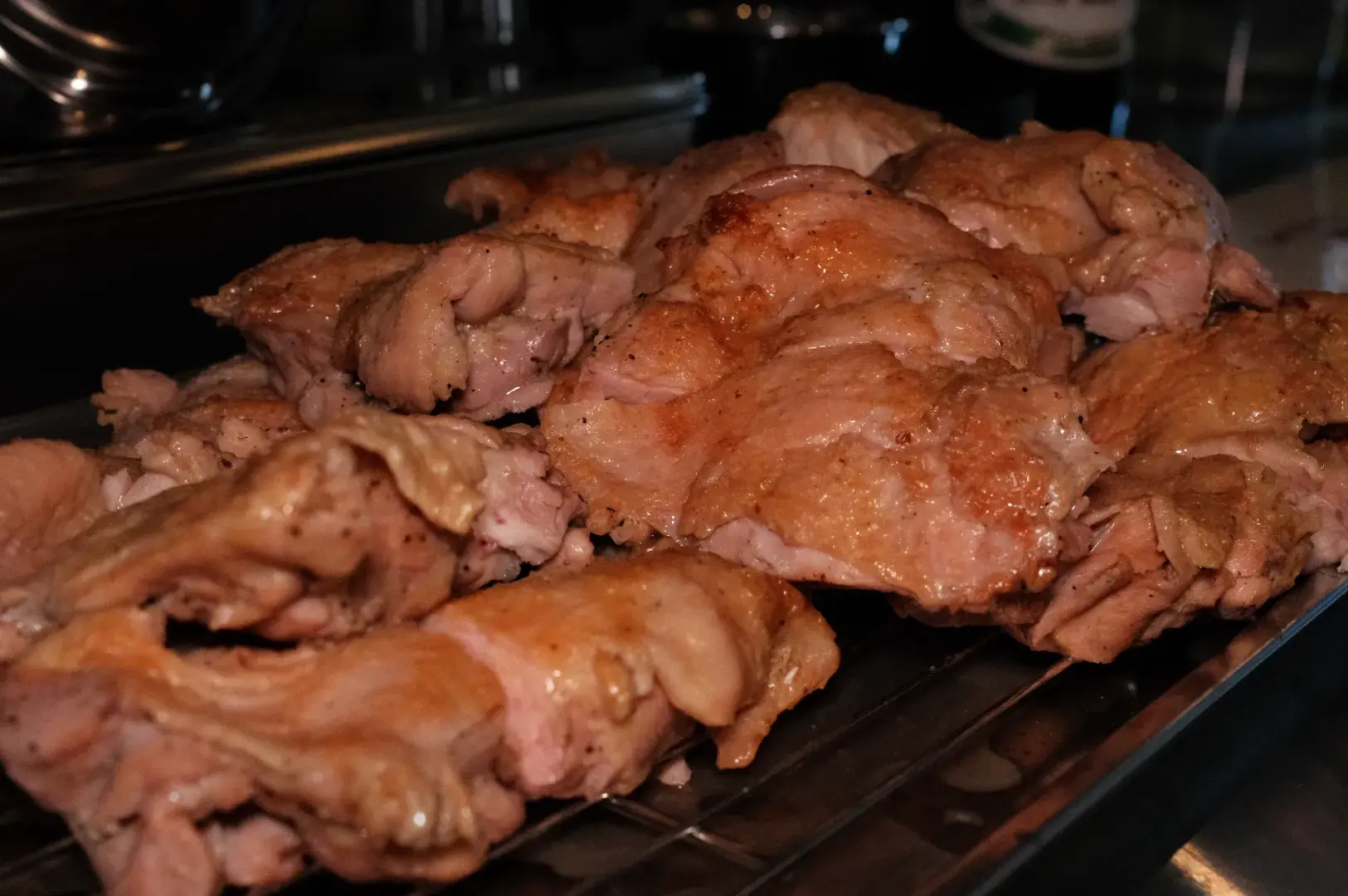 Cooked and browned chicken thighs arranged on a rack.