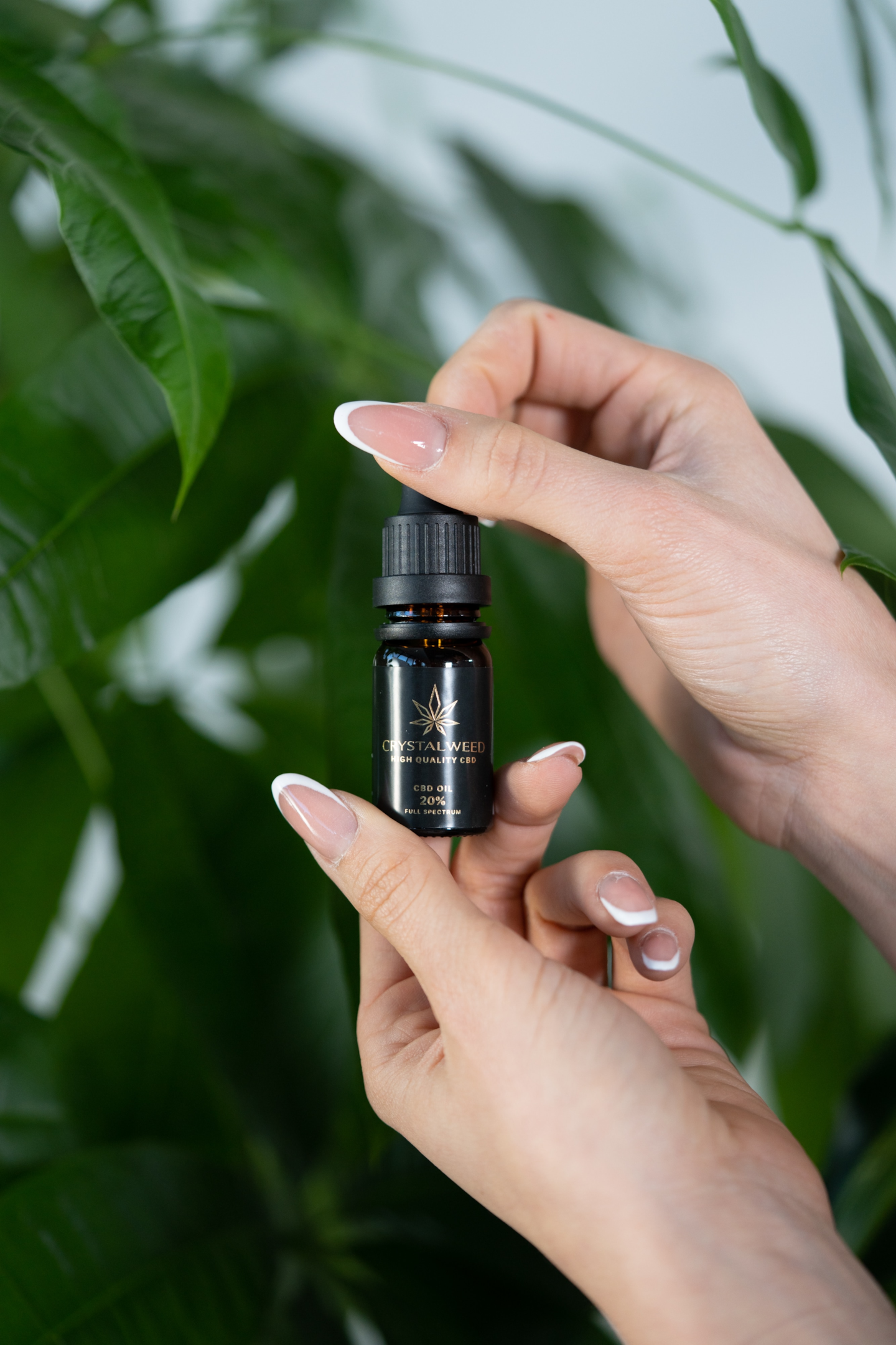 woman's hands holding a small bottle in front of plants