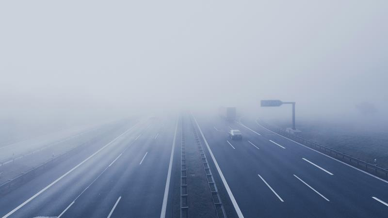 Cars driving into fog on the highway.