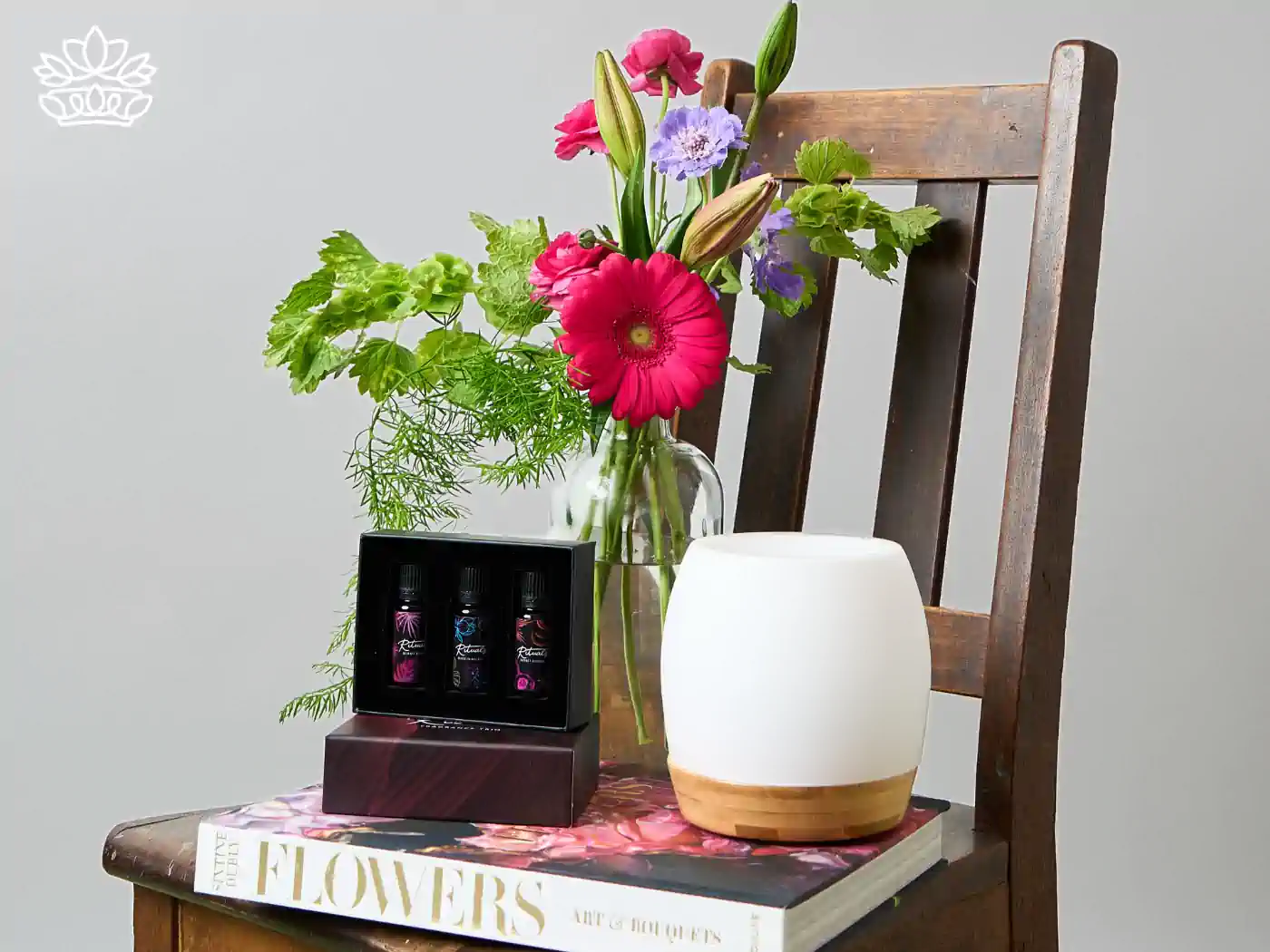 Gift set with essential oils, a diffuser, and fresh flowers on a chair. Gift Boxes for Sister. Delivered with Heart. Fabulous Flowers and Gifts.