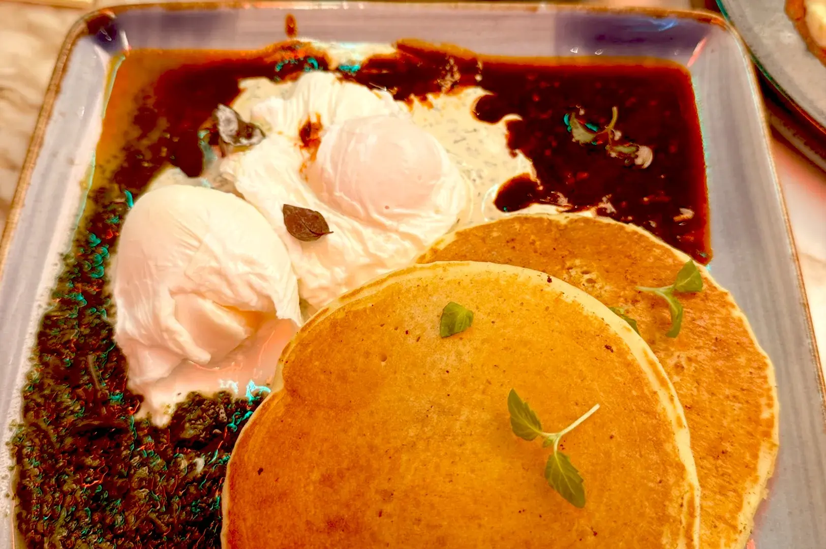 Savory brunch dish featuring fluffy pancakes served with poached eggs and rich sauce at Pancake & Waffle Place by Royz et Vous in Kampong Gelam