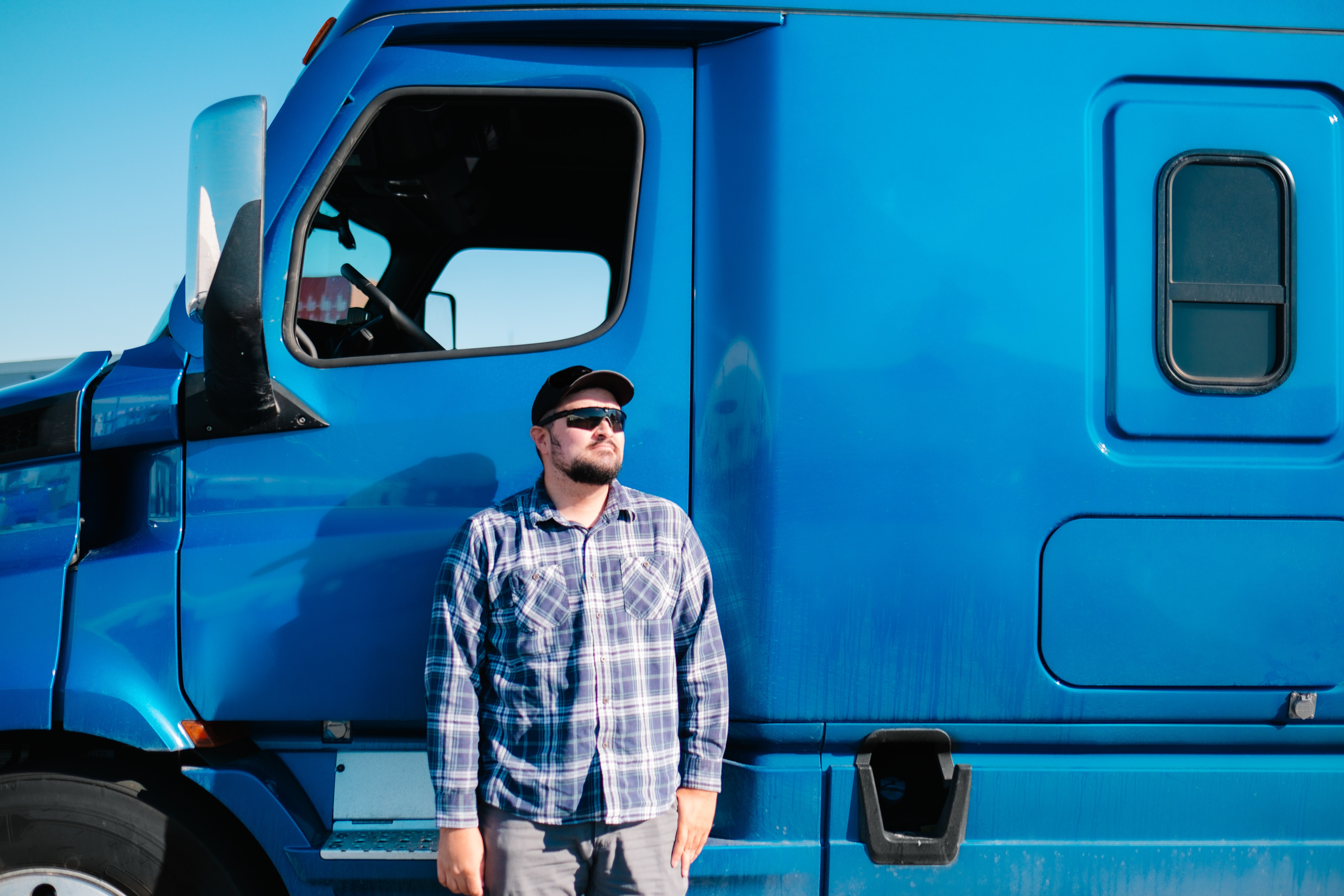 A truck driver standing outside of his semi truck. We offer cross country car transport, door to door service, open carrier and enclosed transport.