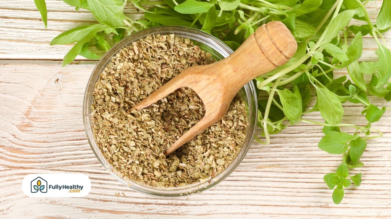 Dried oregano leaves in a bowl next to fresh oregano stems for cooking.