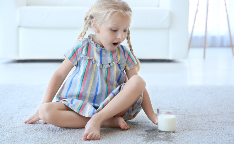 child spilling milk on the carpet