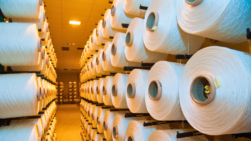 Many rolls of white rayon yarn are stacked in a room