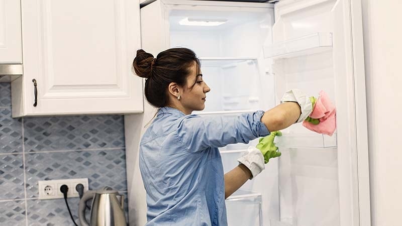 A woman cleaning her fridge doors