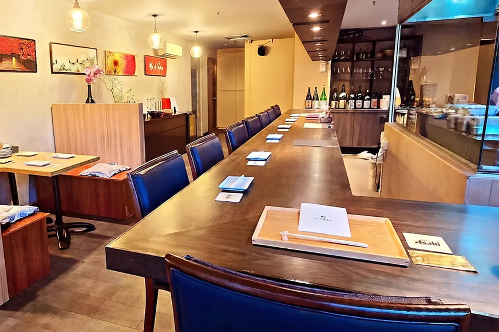 Cozy wooden sushi bar counter at Tetsu Japanese Cuisine with elegant place settings and warm ambient lighting.