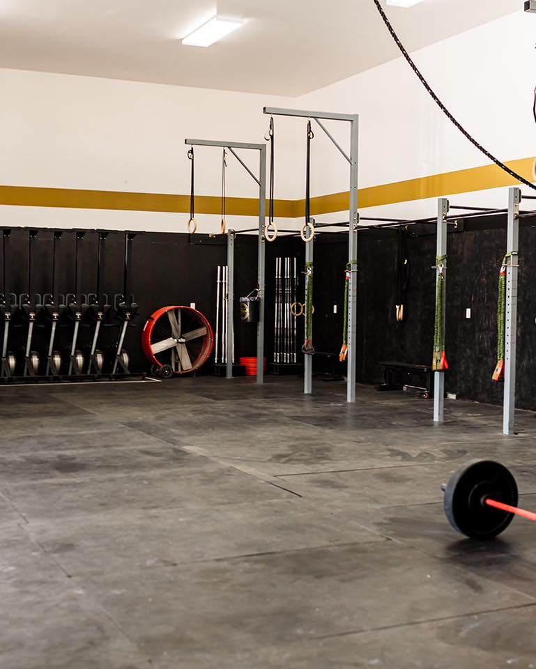 Group of people of different ages and skill levels doing CrossFit exercises in a gym, having fun and achieving their fitness goals