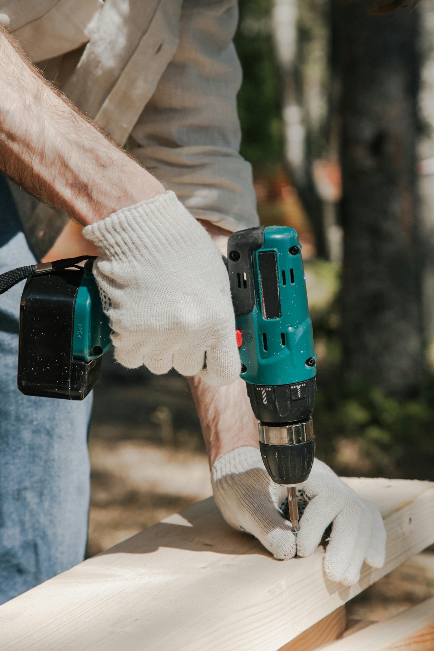 Carpenter with screw gun fixing trim for wood siding