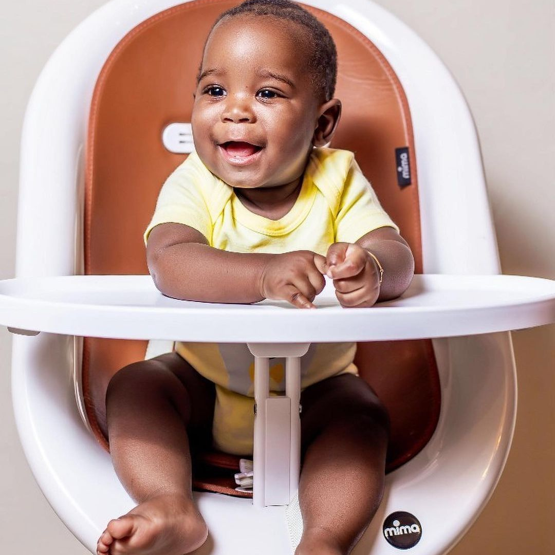 Baby boy sits with a removable tray that Moon high chair use easy.