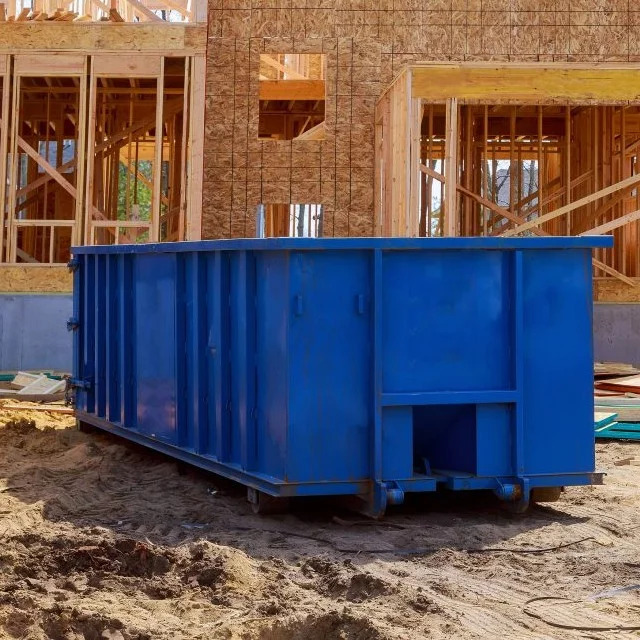 a blue dumpster sitting on top of a pile of dirt